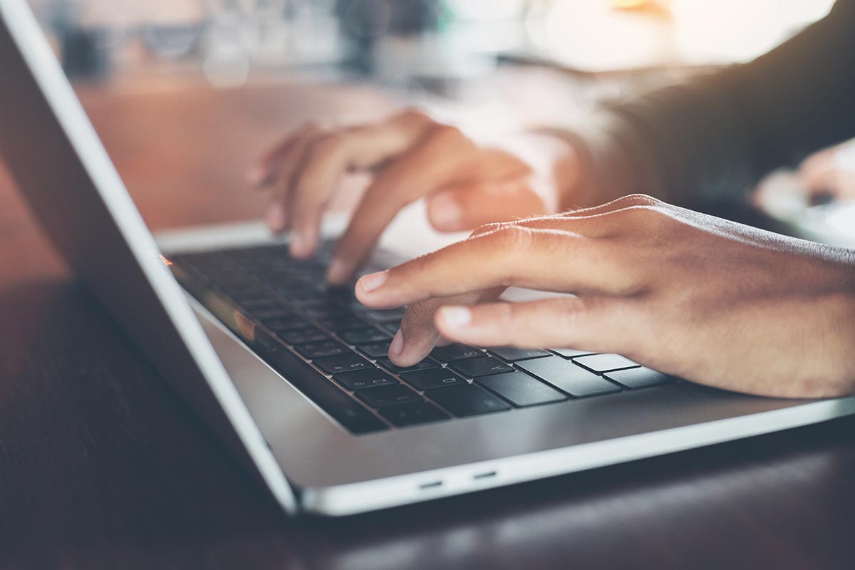 selective focus finger typing on laptop computer marketing on slack channels